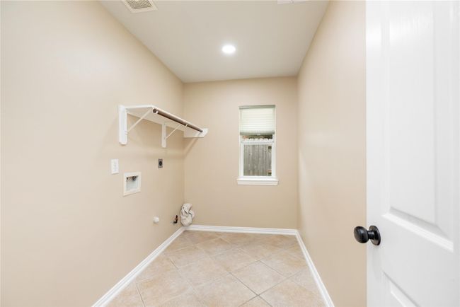 right and thoughtfully designed, the laundry room features durable tile flooring, a window that welcomes natural light, built-in shelving with a hanging rod, and convenient washer and dryer hookups—making chores easier and more organized | Image 34