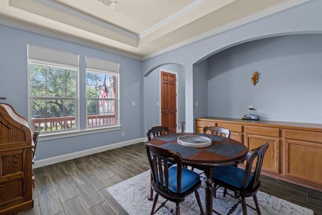 Dining room featuring arched walkways, a tray ceiling, ornamental molding, and wood finish floors | Image 18