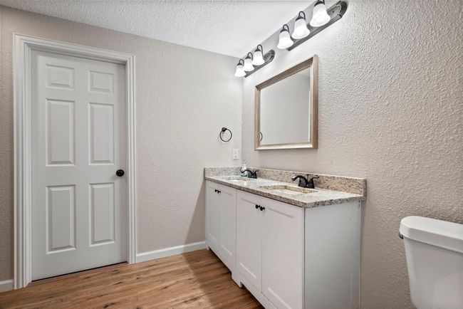 Second floor Primary Bathroom featuring a textured wall, wood finished floors, a sink, and toilet | Image 9