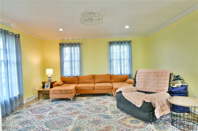 Living area with plenty of natural light, crown molding, baseboards, and visible vents | Image 24