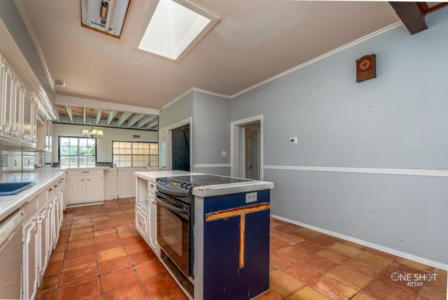 Kitchen featuring white cabinets, white dishwasher, a kitchen island, and crown molding | Image 10