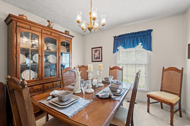 Dining area featuring a textured ceiling, light carpet, baseboards, and a notable chandelier | Image 18