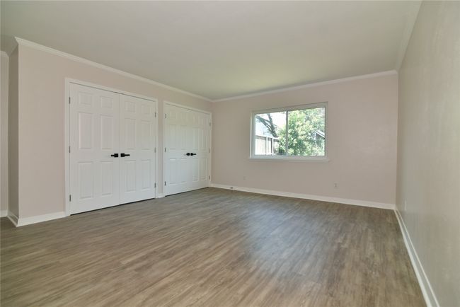Unfurnished bedroom with two closets, wood finished floors, and ornamental molding | Image 26