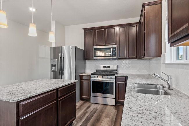 Kitchen with hanging light fixtures, appliances with stainless steel finishes, sink, tasteful backsplash, and light granite countertops | Image 17