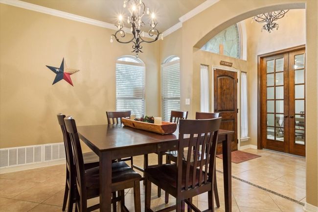 Dining area featuring french doors, crown molding, light tile patterned floors, baseboards, and a chandelier | Image 9