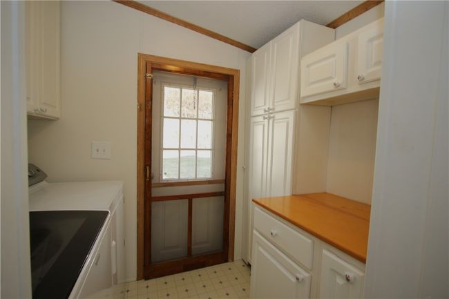 Convenient 8x7 Laundry off Kitchen and back entrance. Addional Storage Cabinets & Folding Table | Image 25