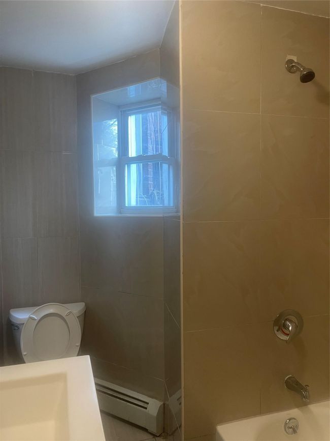 Full bathroom featuring a baseboard heating unit, toilet, and shower / bathtub combination | Image 6