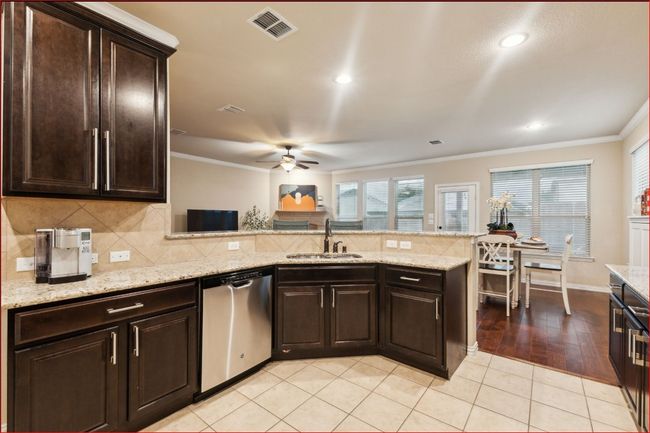 Kitchen with a peninsula, tasteful backsplash, dishwasher, ceiling fan, and ornamental molding | Image 10