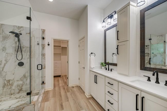 Bathroom featuring a marble finish shower, wood finished floors, double vanity, and a walk in closet | Image 25