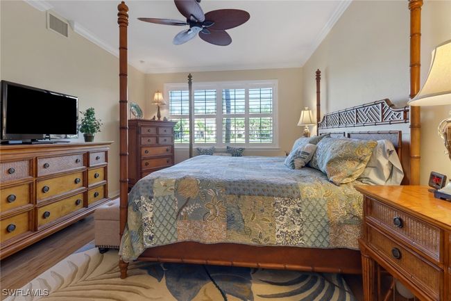 Bedroom with visible vents, crown molding, wood finished floors, and a ceiling fan | Image 14