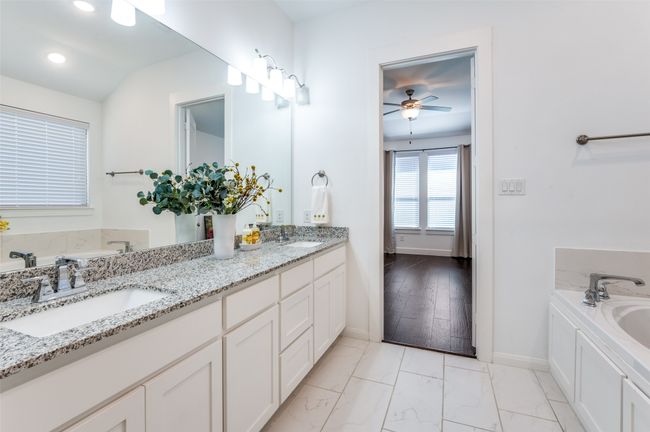 Luxurious master ensuite featuring elegant tile flooring, a dual-sink vanity with a granite countertop, a spacious walk-in closet, a relaxing Texas tub, and a separate walk-in shower. | Image 19