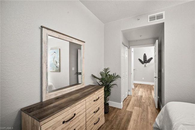 Bedroom with baseboards, visible vents, wood finished floors, and a textured wall | Image 15