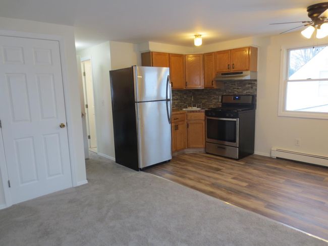 Apartment Kitchen with a ceiling fan, under cabinet range hood, tasteful backsplash, appliances with stainless steel finishes, and a baseboard radiator | Image 10