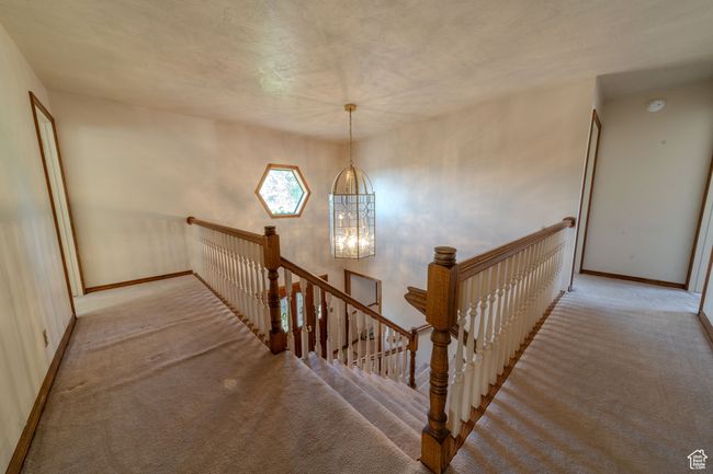 Stairs with baseboards, carpet, and a notable chandelier | Image 19