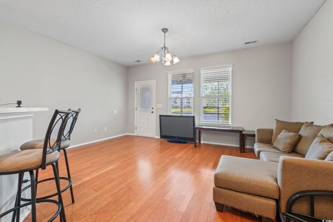 Living area with light wood-type flooring, a chandelier, a textured ceiling, and baseboards | Image 7