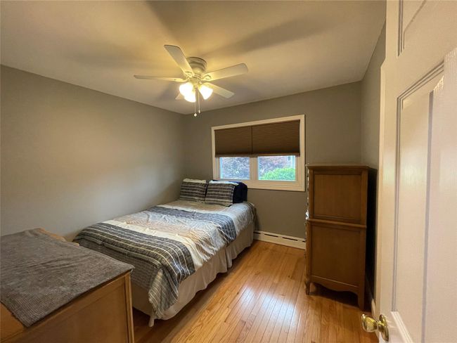 Bedroom with a baseboard heating unit, light wood-type flooring, baseboards, and a ceiling fan | Image 23