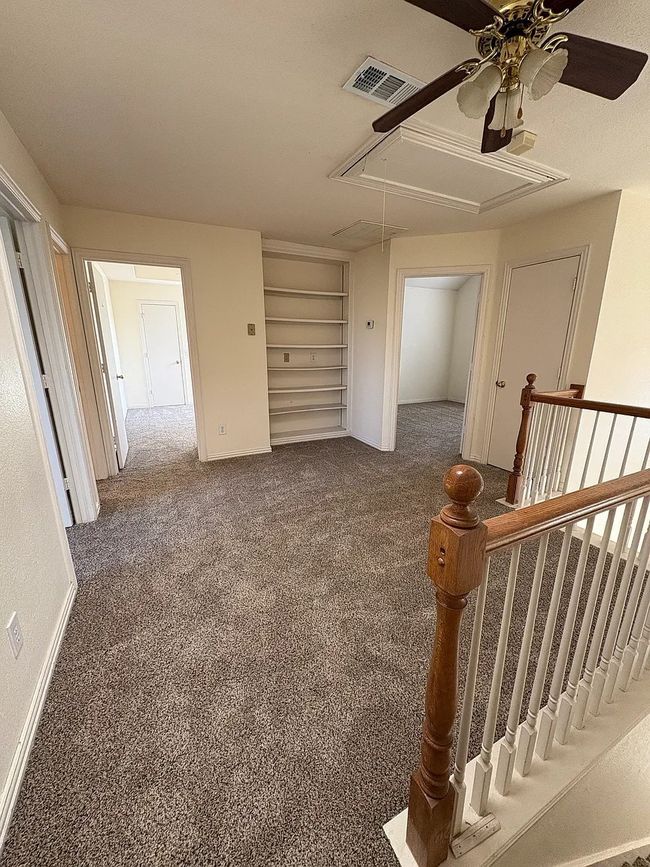 Empty room featuring attic access, ceiling fan, carpet, and built in features | Image 12