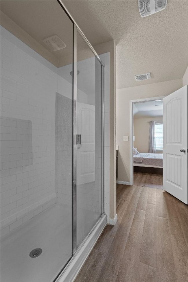 Ensuite bathroom featuring a stall shower, wood finished floors, and a textured ceiling | Image 17