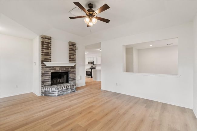 Brick fireplace with mantel serves as a subtle focal point in the open living area. | Image 4