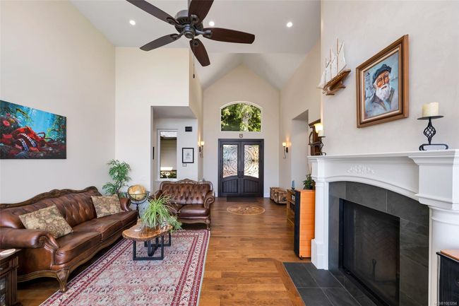 Living room with high vaulted ceiling, ceiling fan, wood finished floors, a tiled fireplace, and recessed lighting | Image 33