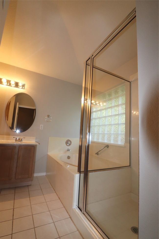 Full bathroom featuring a garden tub, a stall shower, vanity, tile patterned floors, and lofted ceiling | Image 23