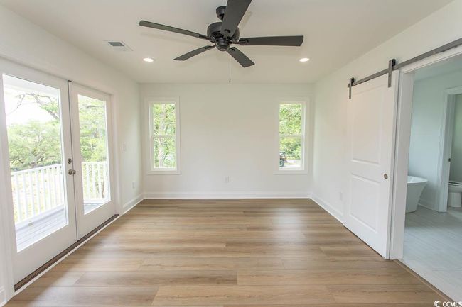 Master room with a barn door, ceiling fan, recessed lighting, light wood finished floors, and baseboards | Image 23
