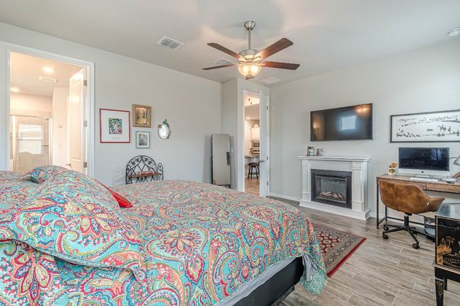 Bedroom with wood finished floors, a glass covered fireplace, a ceiling fan, and a desk | Image 17