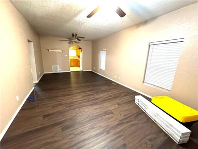 Empty room with a textured ceiling, ceiling fan, and dark wood-type flooring | Image 2