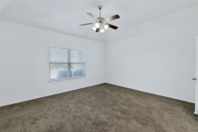 Empty room featuring dark colored carpet, ceiling fan, and vaulted ceiling | Image 13