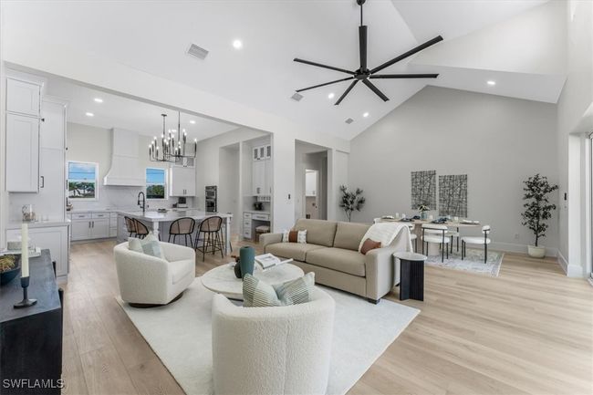Living room featuring high vaulted ceiling, a chandelier, recessed lighting, light wood-style flooring, and a ceiling fan | Image 26