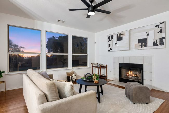 Living room featuring visible vents, baseboards, a tiled fireplace, a ceiling fan, and wood finished floors | Image 7
