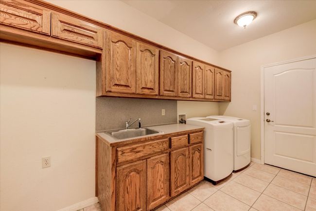 Ample laundry room with cabinets, a sink, cabinet space, washer and clothes dryer, and space for additional refrigerator | Image 16
