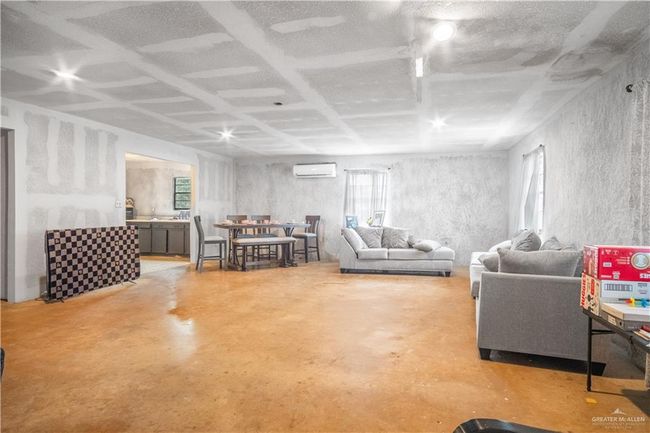 Living area featuring finished concrete floors and an AC wall unit | Image 6