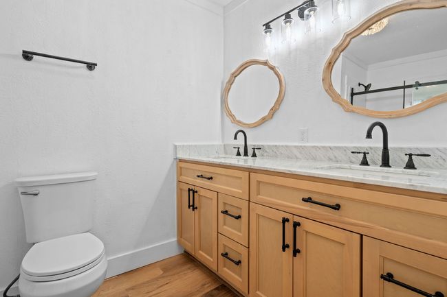 Bathroom featuring double vanity, a sink, toilet, and wood finished floors | Image 30