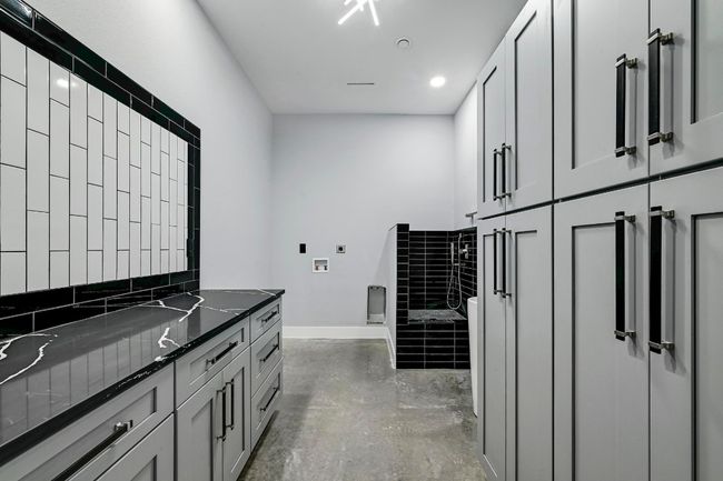 Amazing oversized main floor laundry room with extensive cabinetry storage, large folding vanity, modern sink, and a dog wash station! | Image 34