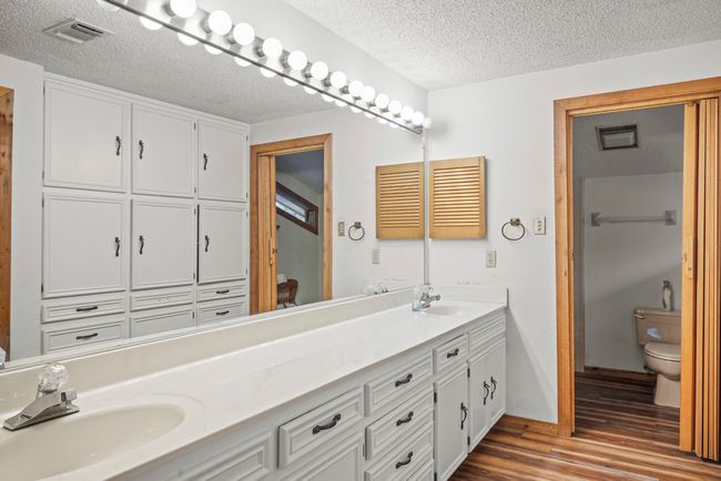 Bathroom featuring double vanity, wood finished floors, and a textured ceiling | Image 24