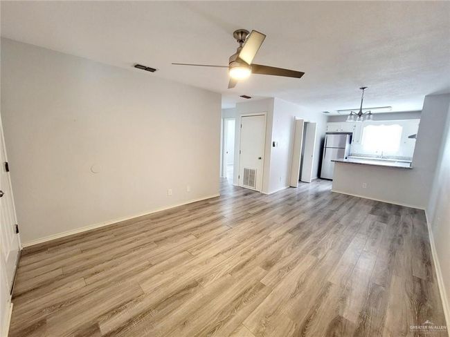 Unfurnished living room featuring light wood-type flooring, a chandelier, and ceiling fan | Image 15