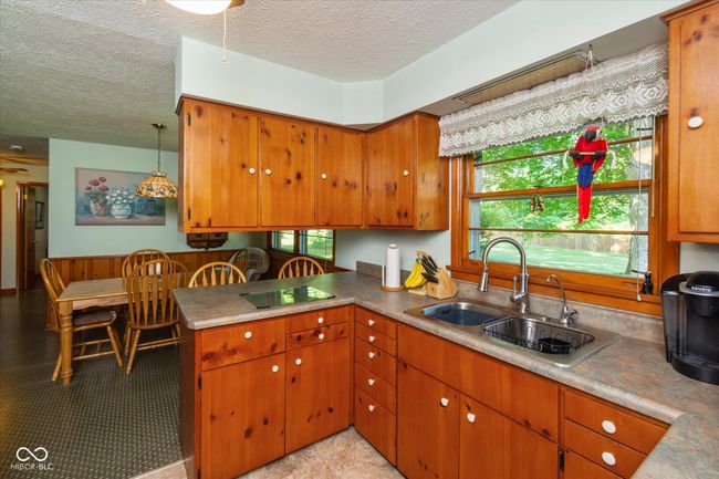 kitchen featuring a textured ceiling, black electric stovetop, brown cabinetry, and healthy amount of natural light | Image 11