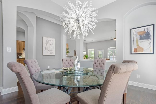 Dining space with arched walkways, wood finished floors, baseboards, and a chandelier | Image 5