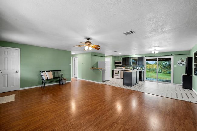 Unfurnished living room with light wood finished floors, a ceiling fan, and a textured ceiling | Image 7