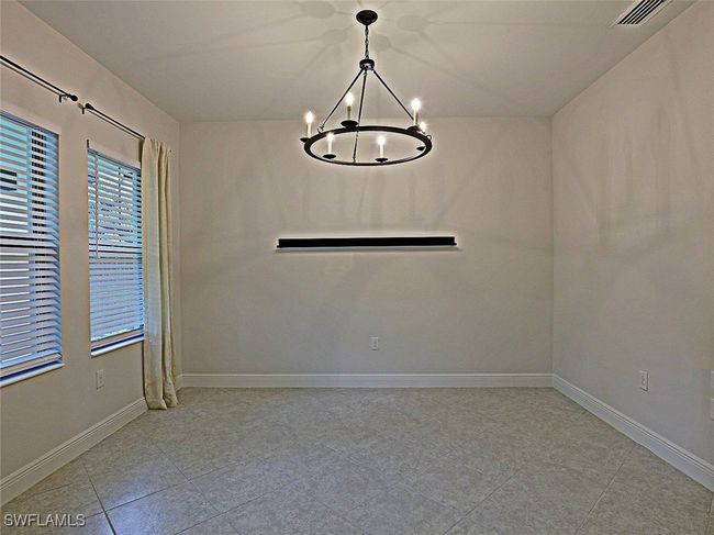 Empty room with a chandelier, baseboards, and light tile patterned floors | Image 24