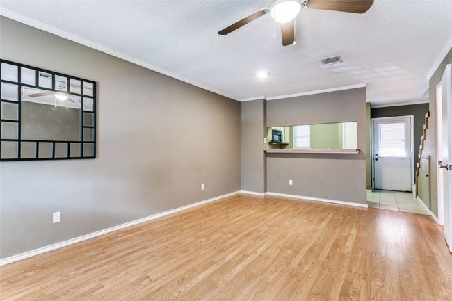 Empty room with ceiling fan, ornamental molding, wood finished floors, and a textured ceiling | Image 8