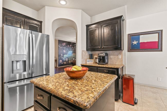 Kitchen featuring tasteful backsplash, a center island, dark brown cabinetry, and stainless steel fridge with ice dispenser | Image 16