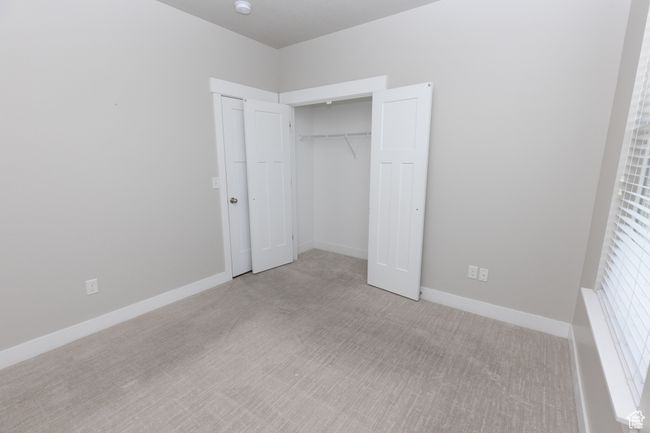 Unfurnished bedroom featuring light colored carpet, a closet, and baseboards | Image 16