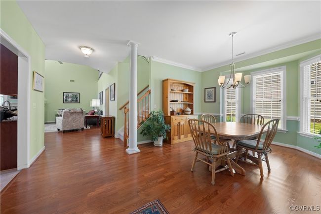 Dining area featuring wood finished floors, stairway, a chandelier, ornamental molding, and decorative columns | Image 7
