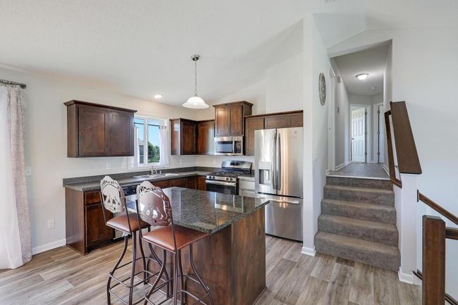 The kitchen boasts beautiful dark cabinetry paired with sleek stainless steel appliances, creating a modern and sophisticated cooking space. | Image 14