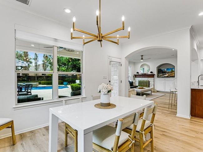 Dining room featuring light wood-type flooring, arched walkways, ornamental molding, and a fireplace | Image 12