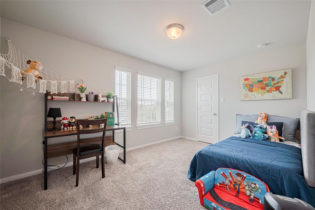 This bedroom is bright and cozy, featuring a large window, plush carpet, and neutral walls. | Image 43