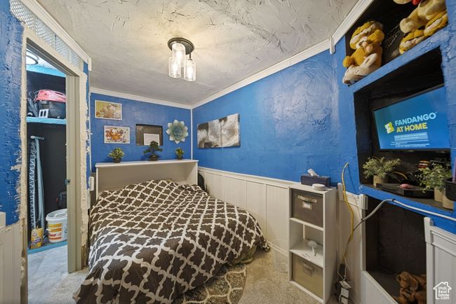 Bedroom featuring a textured wall, ornamental molding, and wainscoting | Image 12