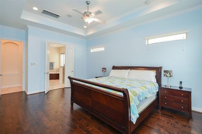 Spacious primary bedroom with wood flooring. | Image 19